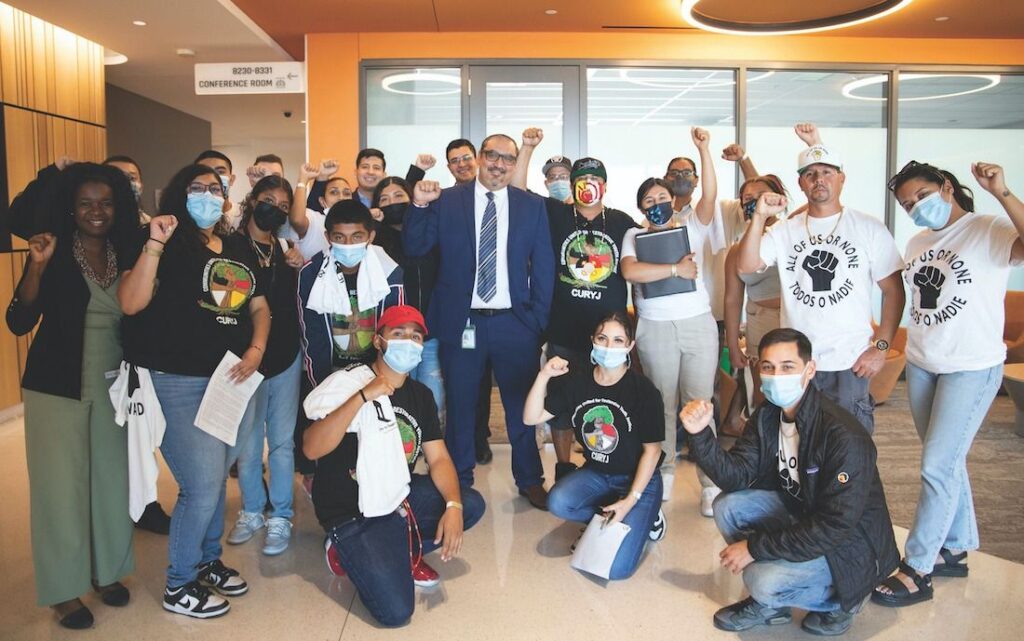 About 20 people holding up their fist for a group photo